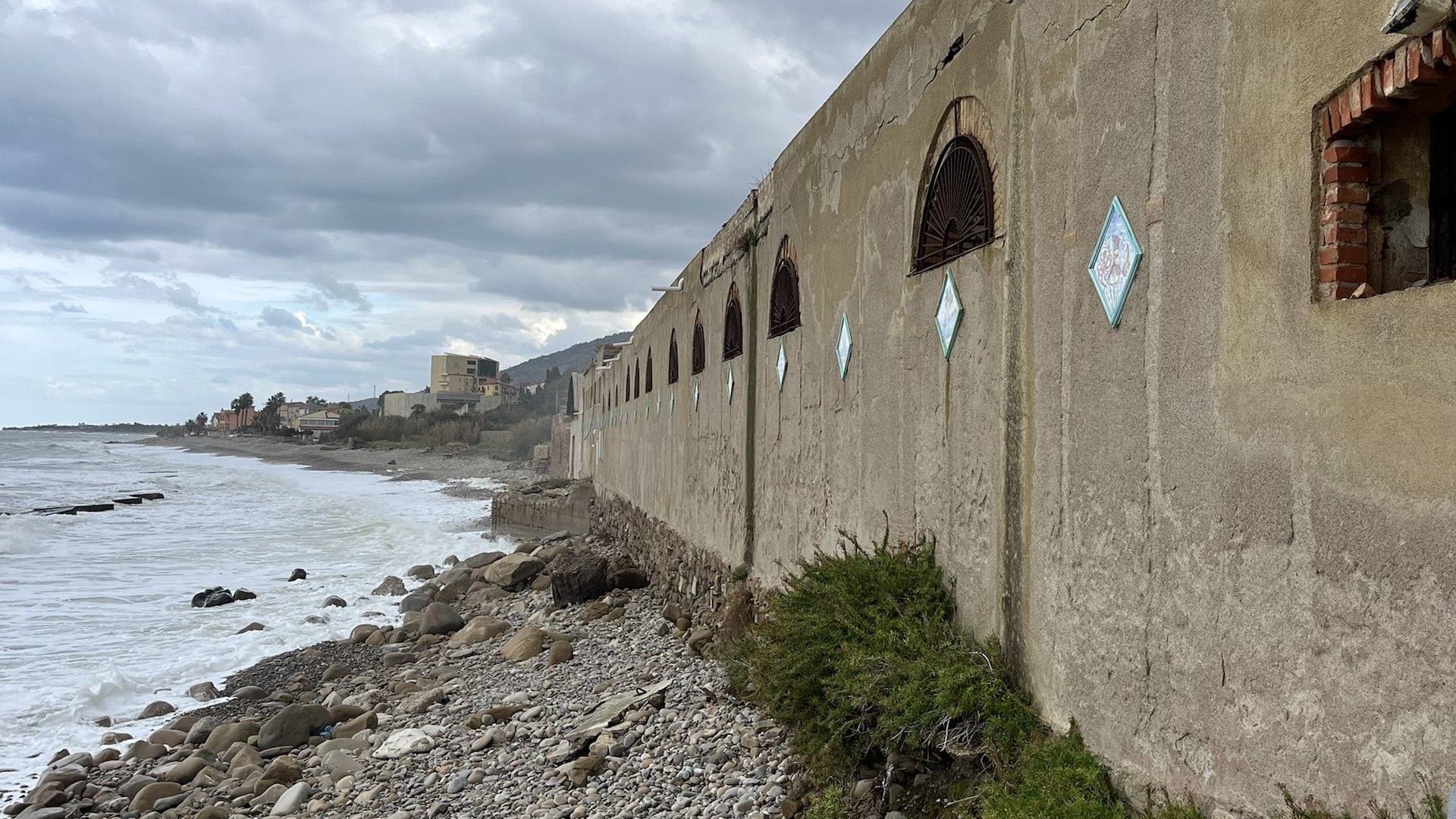 Il fronte a mare dell'ex fabbrica, con gli archi e i decori in ceramica, sulla spiaggia di ciottoli