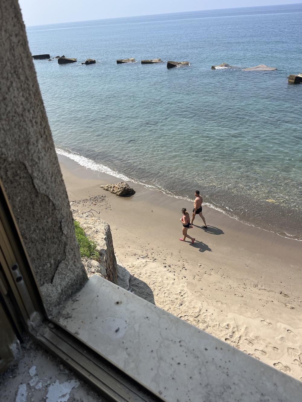 La spiaggia e il mare turchese visti da una finestra dell'edificio